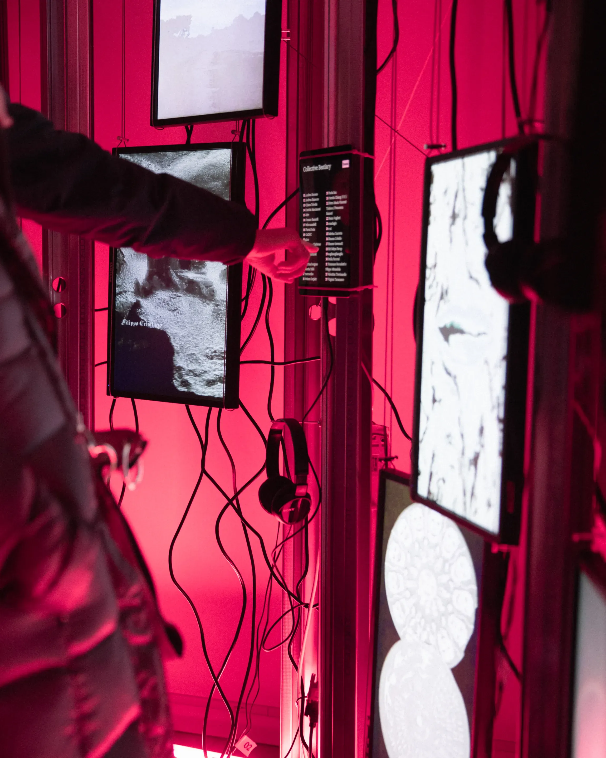 A person interacting with a ipad showing the name of the participants of An Ecology of Beasts collective design exhibition