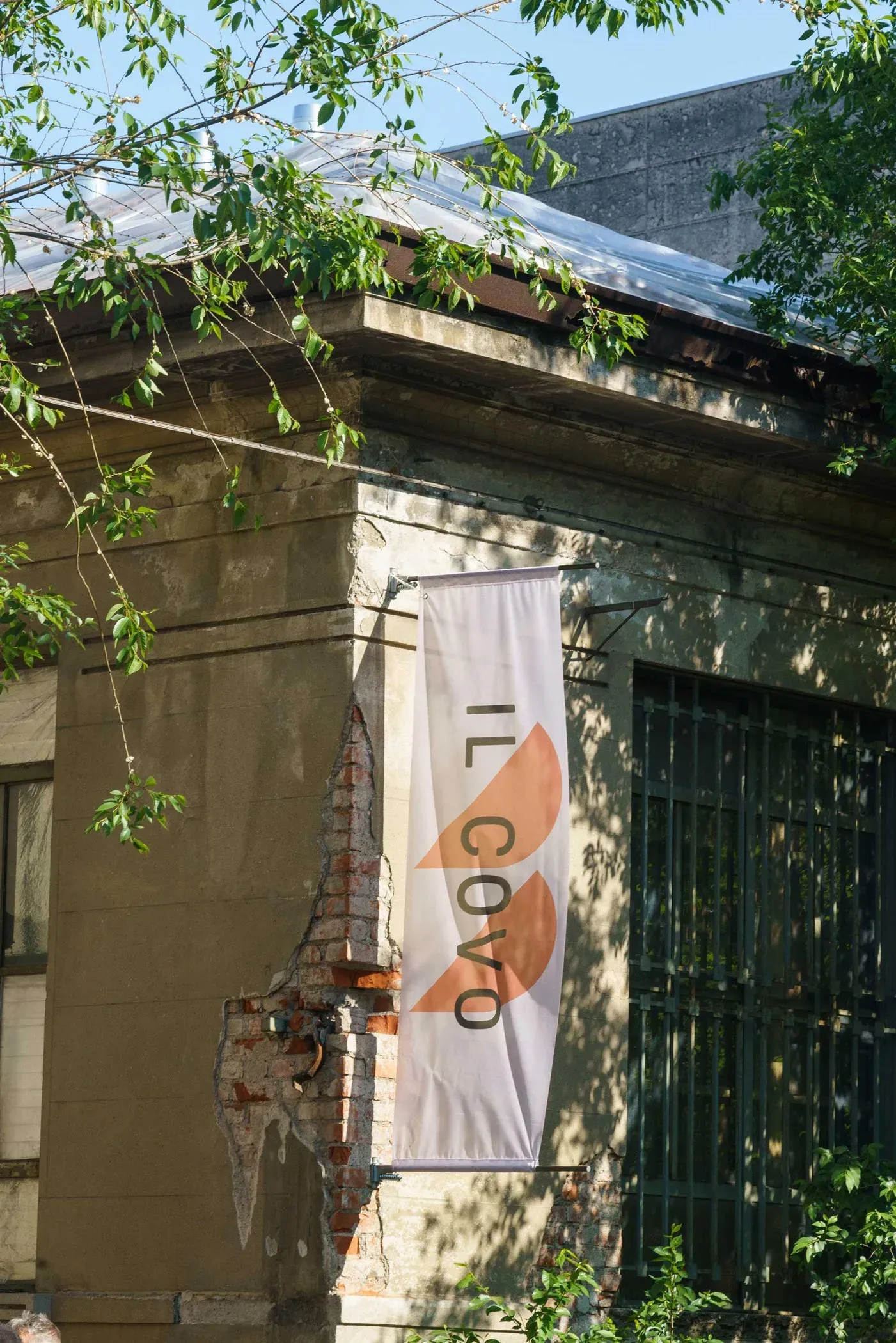 Alcova exhibition banner displayed on the facade of the former Porta Vittoria Abattoir building in Milan.